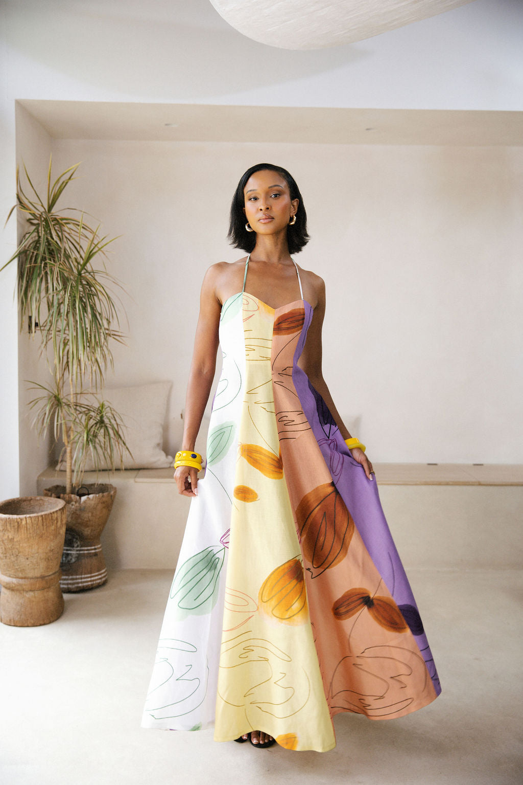 Woman wearing a colorful dress with abstract patterns in a minimal indoor setting.